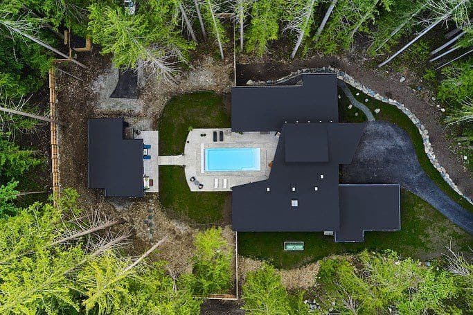 Aerial view of a modern house with pool amid forested surroundings in Victoria BC.