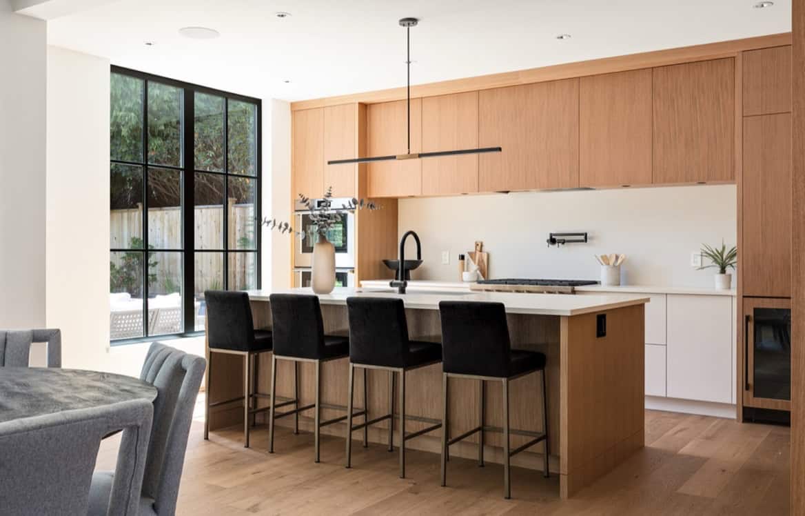 Modern kitchen with wooden cabinetry, large island, and black bar stools in Victoria BC home.