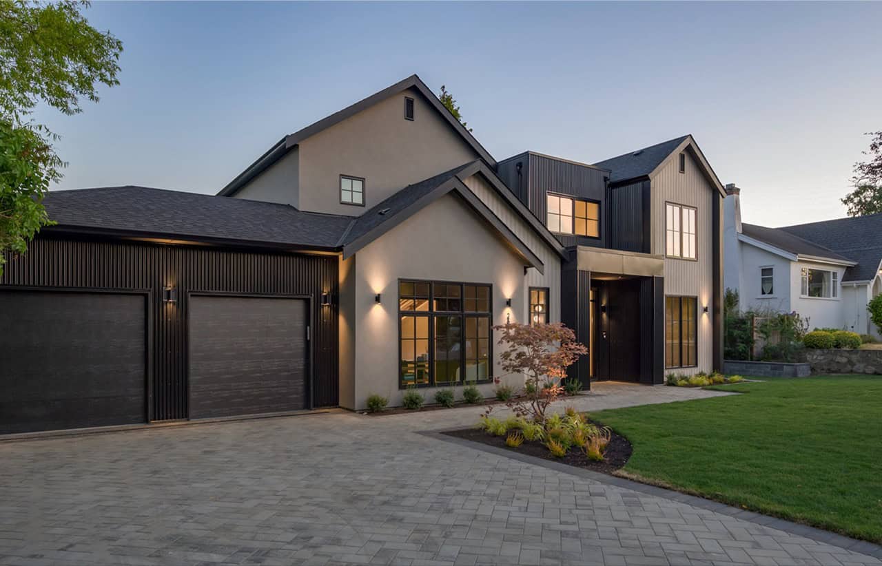 Modern luxury home by White Wolf Homes in Victoria BC with dark garage doors and landscaped front.