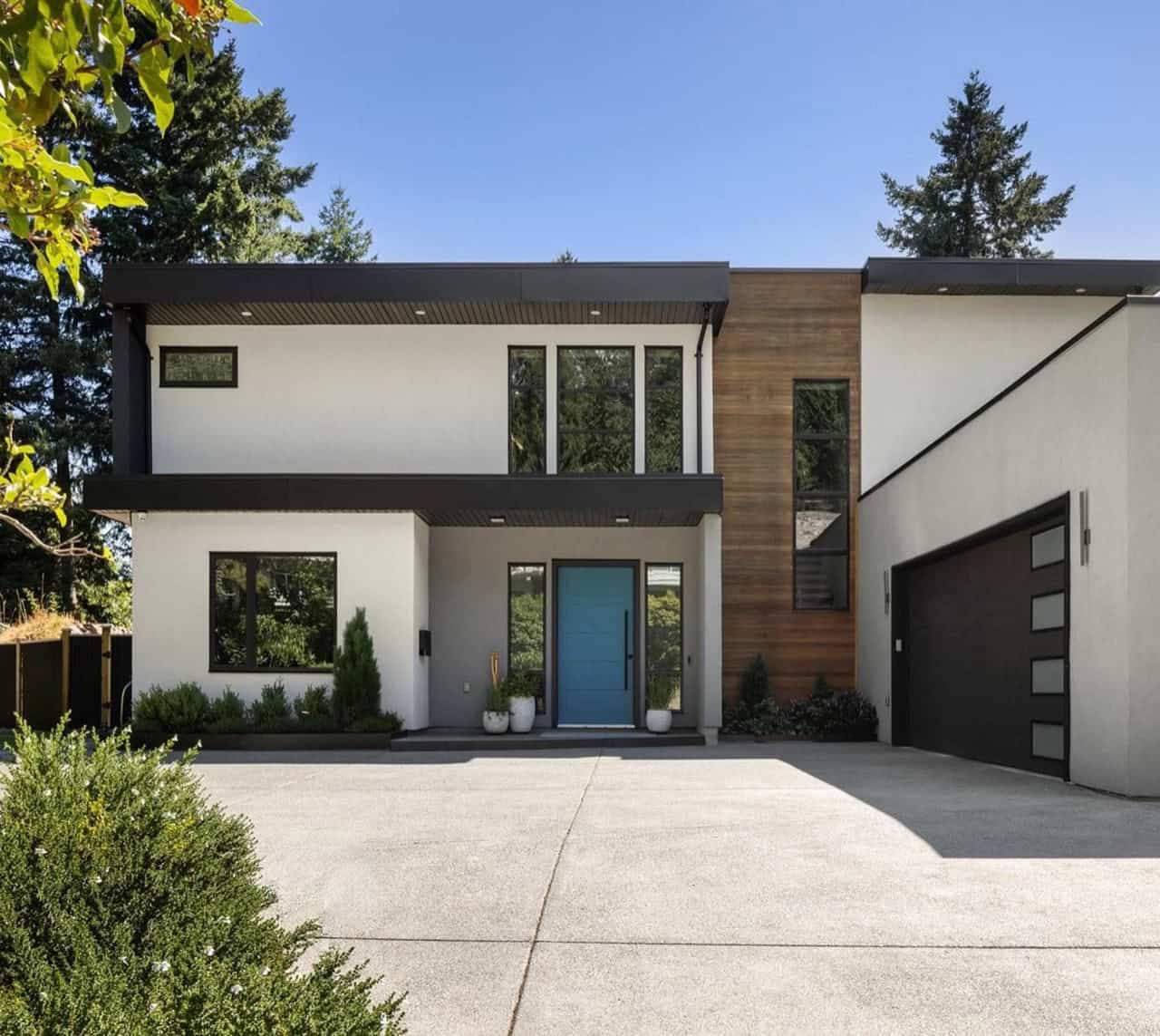Contemporary two-story custom home with blue front door and sleek garage in Victoria BC.