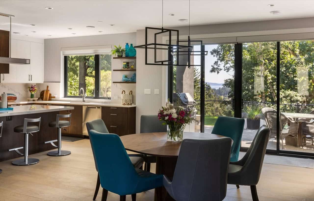 Open-plan kitchen and dining area with modern seating and large windows.