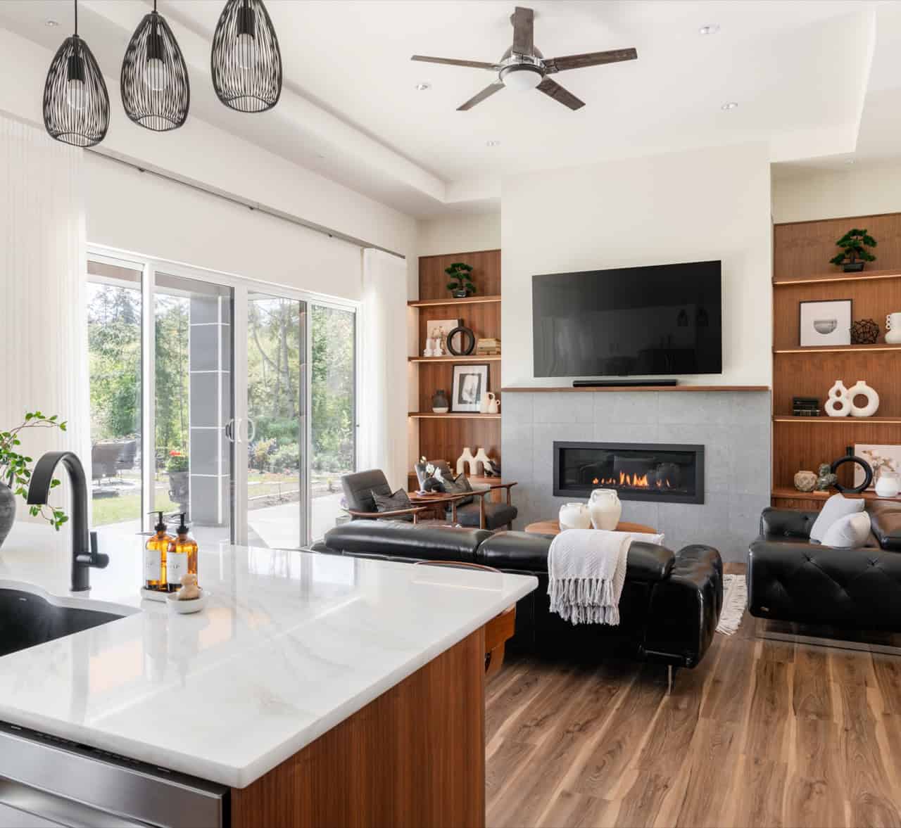 Bright open living room with large windows, built-in shelves, and a wall-mounted TV.