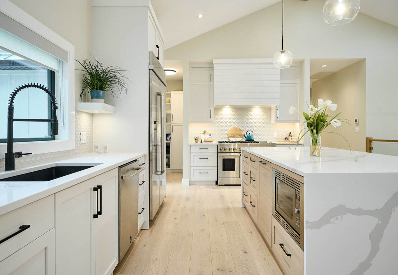 Modern white kitchen by White Wolf Homes in Langford, Victoria BC with island and stainless appliances.