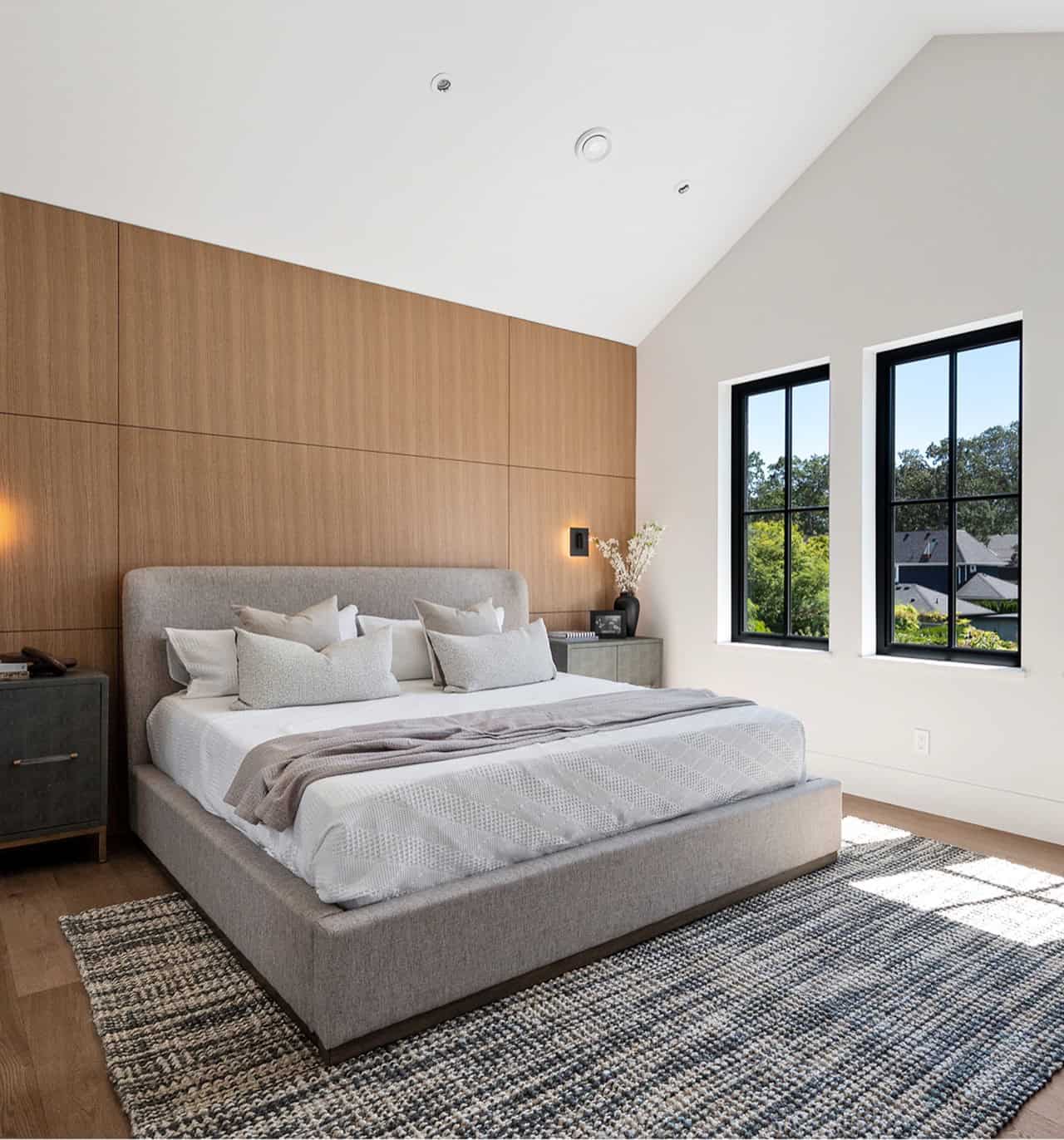 Modern bedroom in a custom home by White Wolf Homes in Victoria BC with large windows and a wooden alcove.