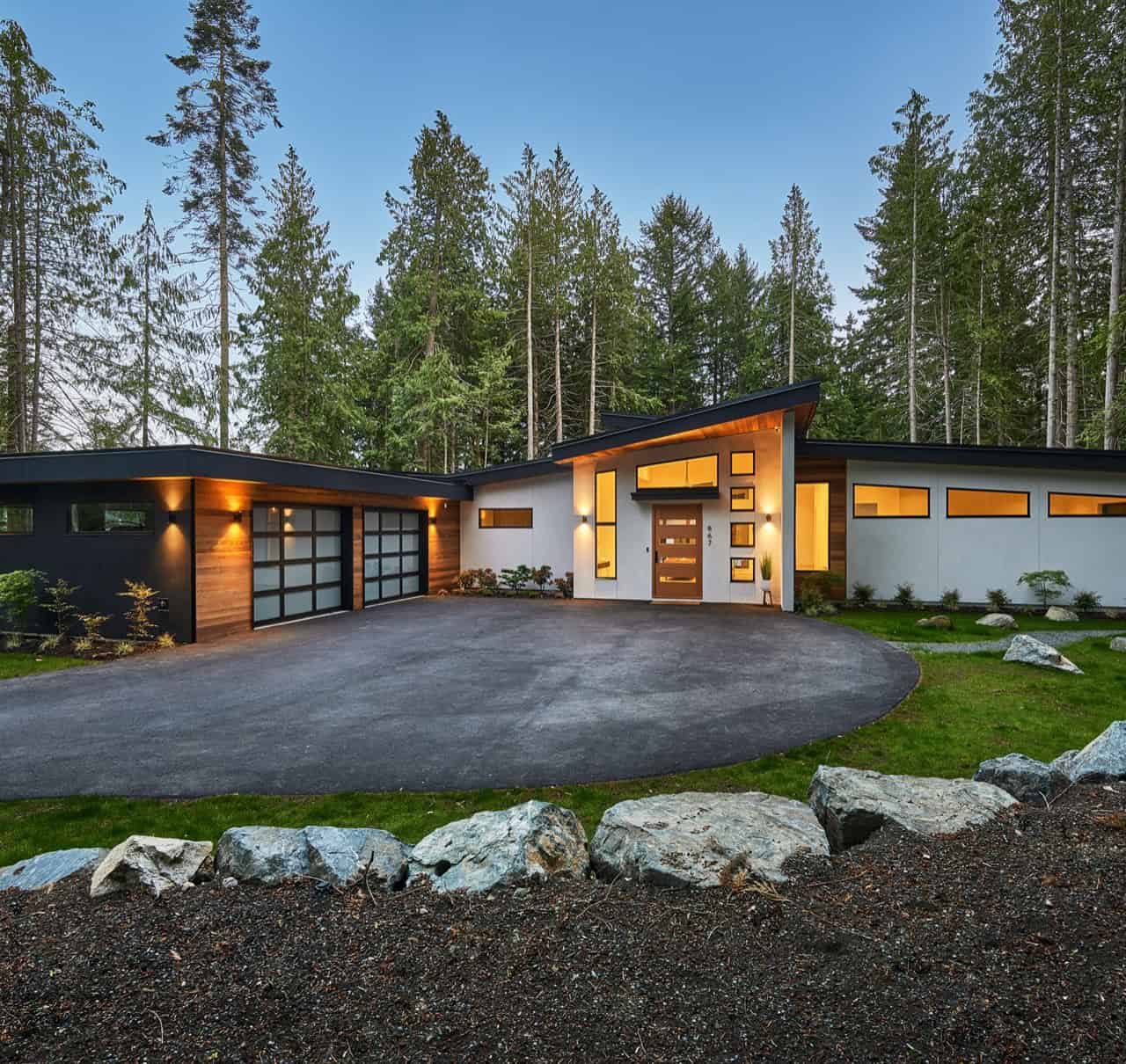 Modern custom home by White Wolf Homes on Vancouver Island with expansive driveway and wooded setting.