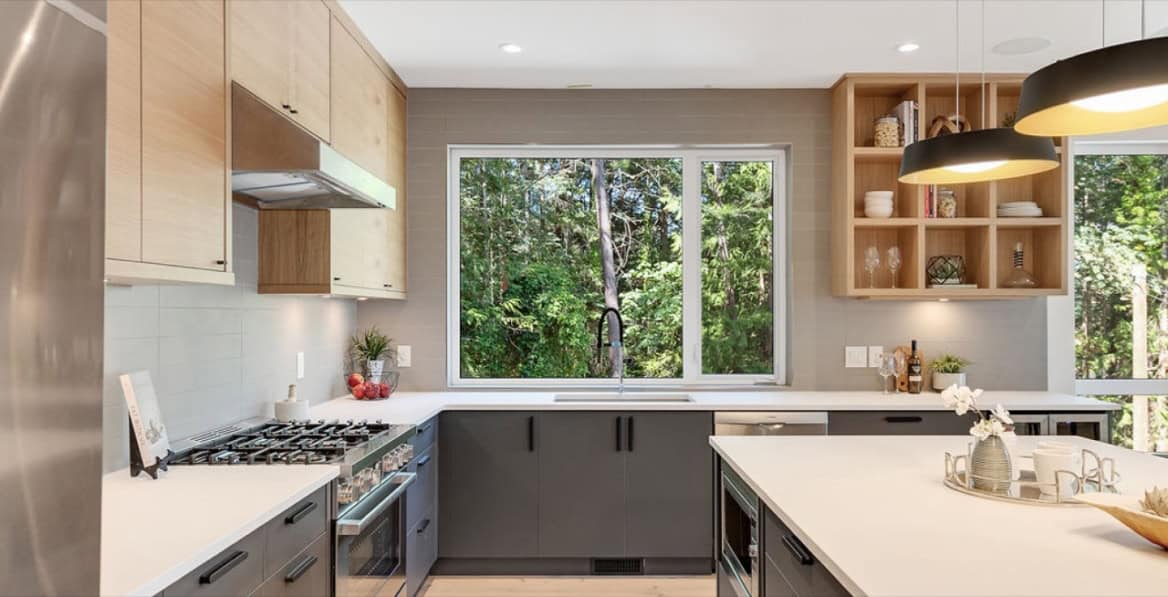 Modern kitchen with large window, grey cabinets, and island in a White Wolf Homes custom home.