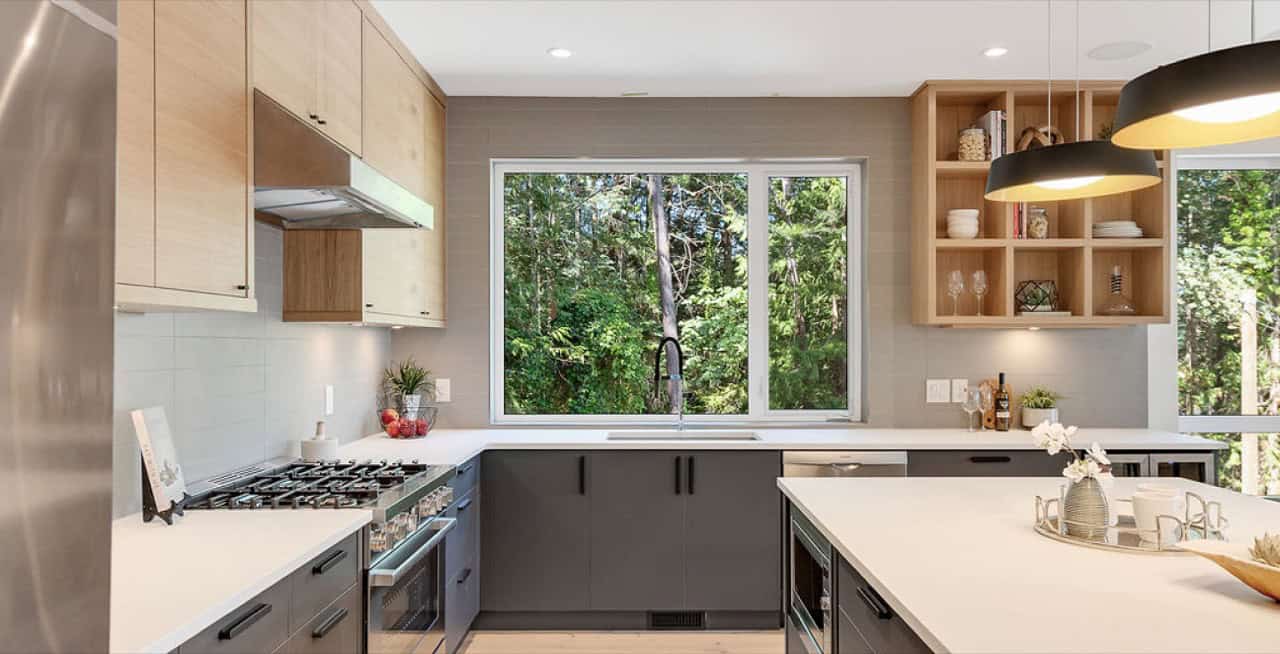 Modern kitchen with large window, grey cabinets, and island in a White Wolf Homes custom home.