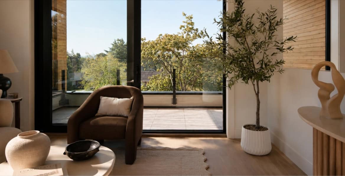 Bright living room opens to a balcony with greenery and natural light.