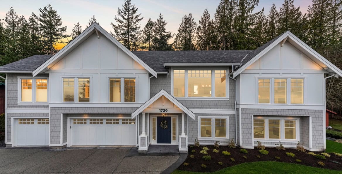 Modern Victoria BC custom home with white siding, multiple gabled roofs and large windows.
