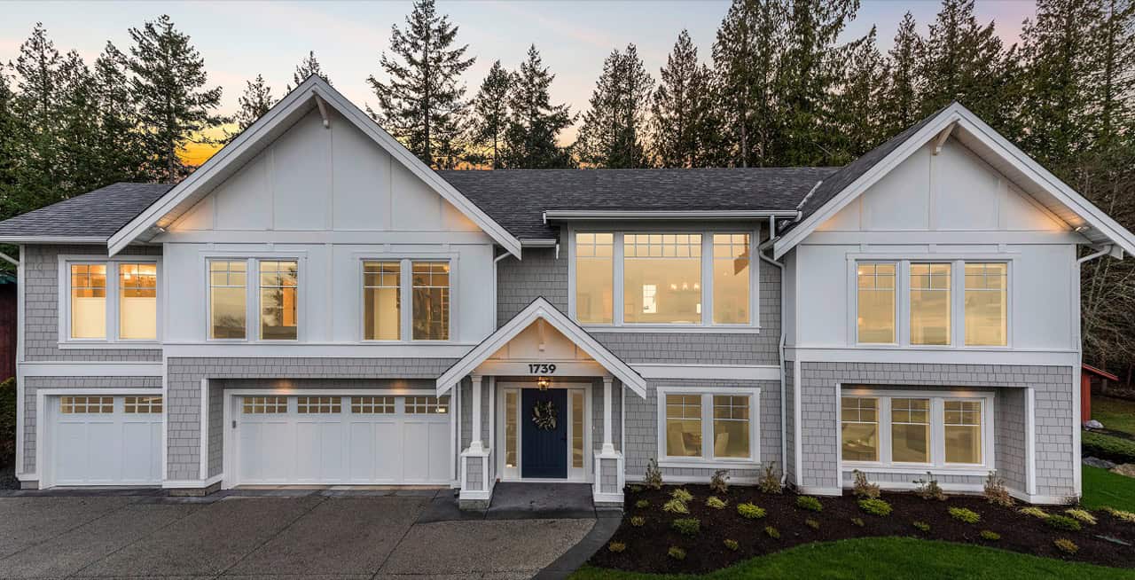 Modern Victoria BC custom home with white siding, multiple gabled roofs and large windows.