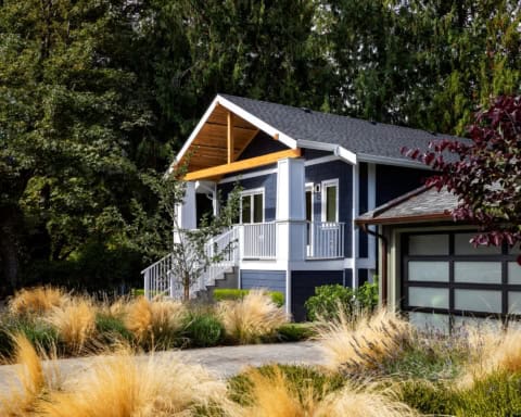 Blue modern home with a covered porch, zen front yard, and natural landscaping in Victoria BC.