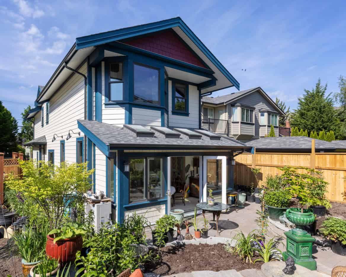 Exterior view of a modern two-story custom home with blue trim, large windows, and a landscaped yard.