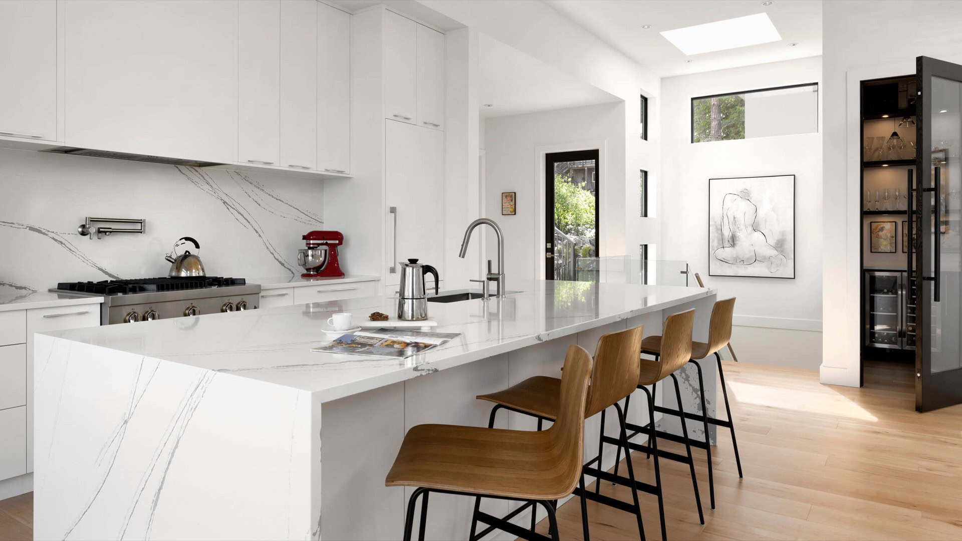 Modern white kitchen with marble countertops and wooden bar stools in a White Wolf Homes custom home.