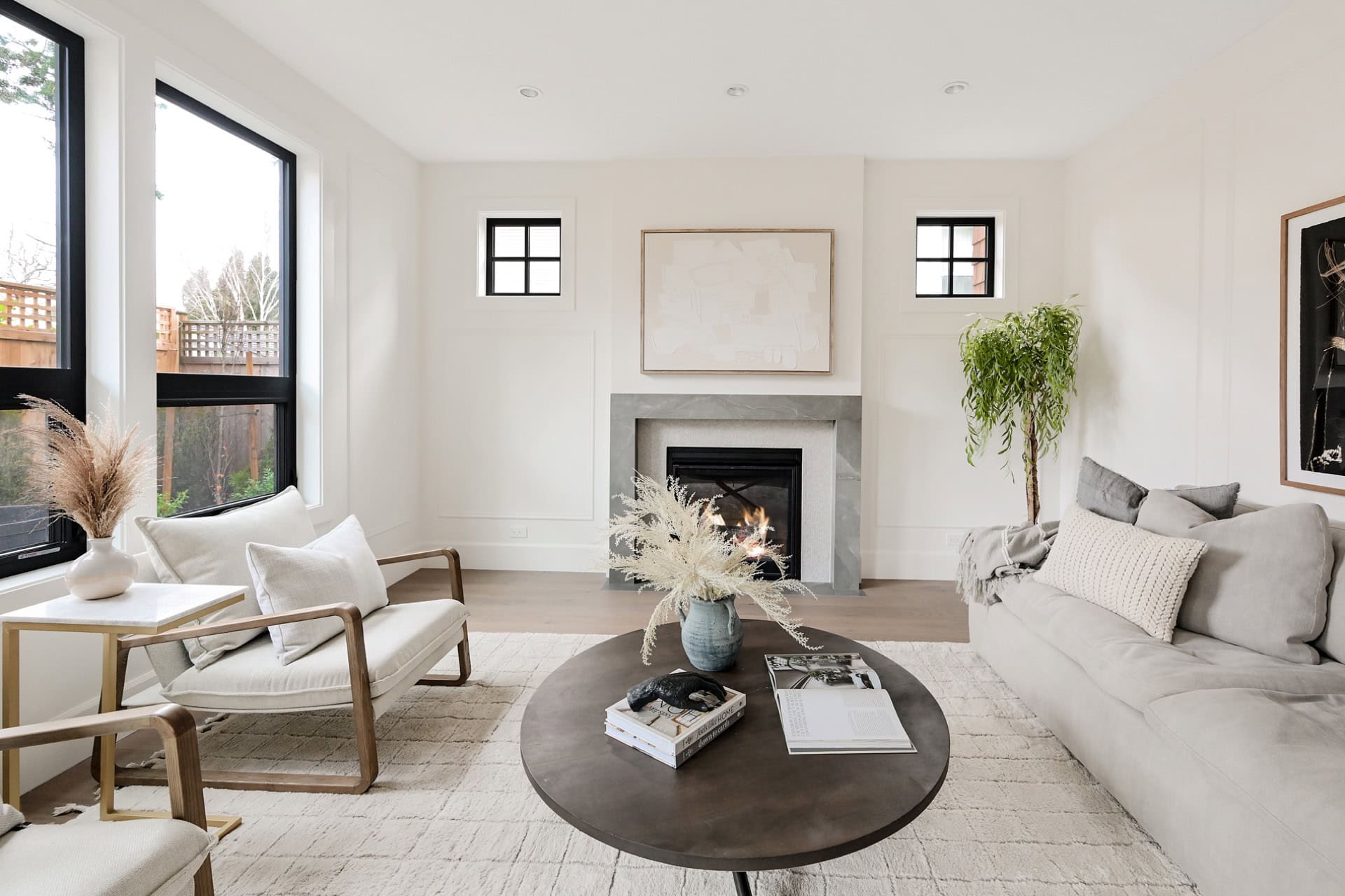 Bright living room with fireplace, white walls, and contemporary gray sofa in Westwyn home.