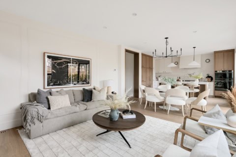 Modern living room with light gray sofa, round coffee table, and open kitchen in a bright, airy home.