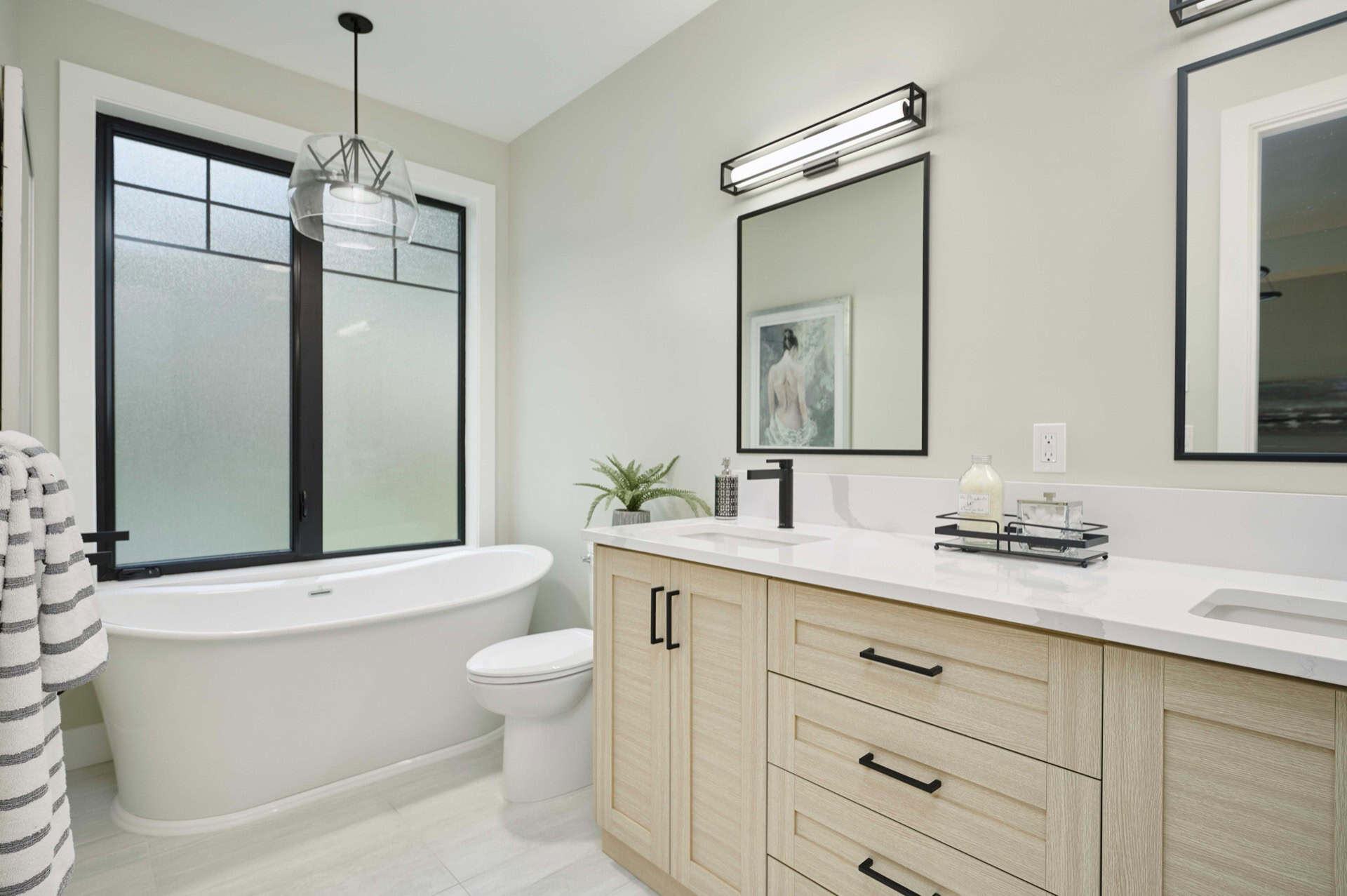 Modern bathroom with freestanding tub and double vanity in light wood cabinetry.