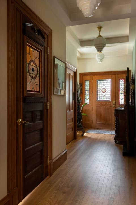 Victorian-style entry hallway with wooden doors and stained glass panels by White Wolf Homes.