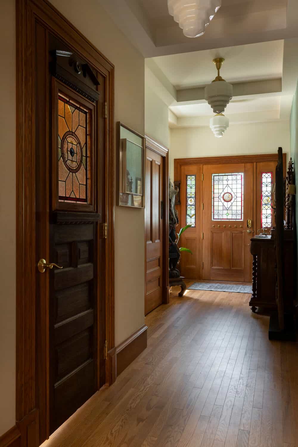 Victorian-style entry hallway with wooden doors and stained glass panels by White Wolf Homes.