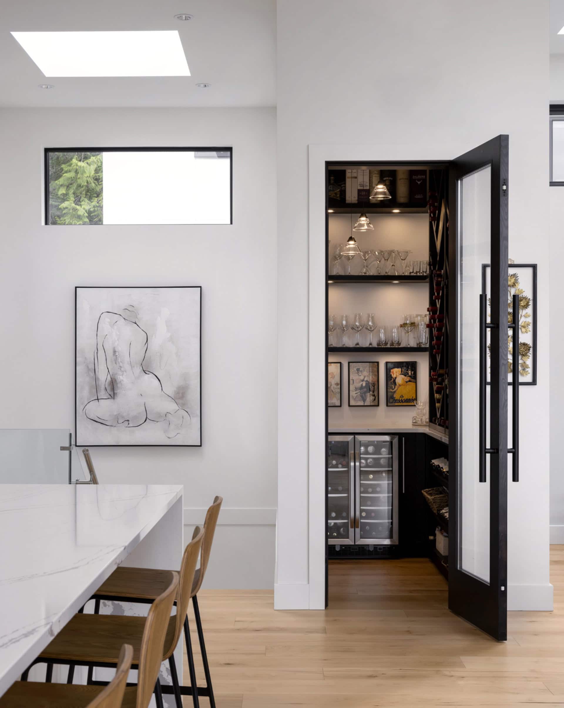 Interior view of a modern kitchen and dining area with a black glass door to a wine cabinet.
