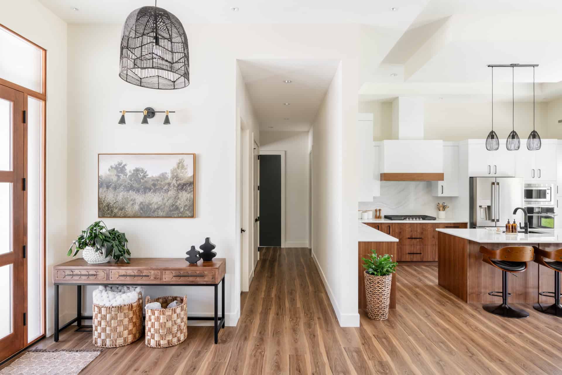 Bright open living space with entry hallway, wooden floor, and modern kitchen in Victoria BC home by White Wolf Homes.