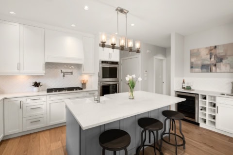 Bright white modern kitchen with island and pendant lighting in Victoria BC home.