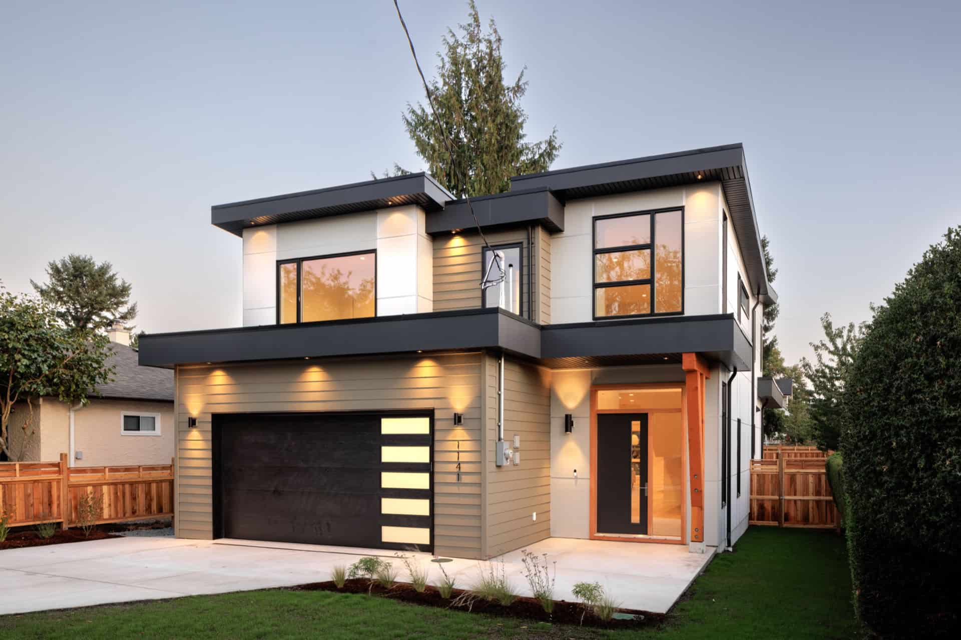 Modern two-story custom home in Victoria BC with illuminated entry and garage.
