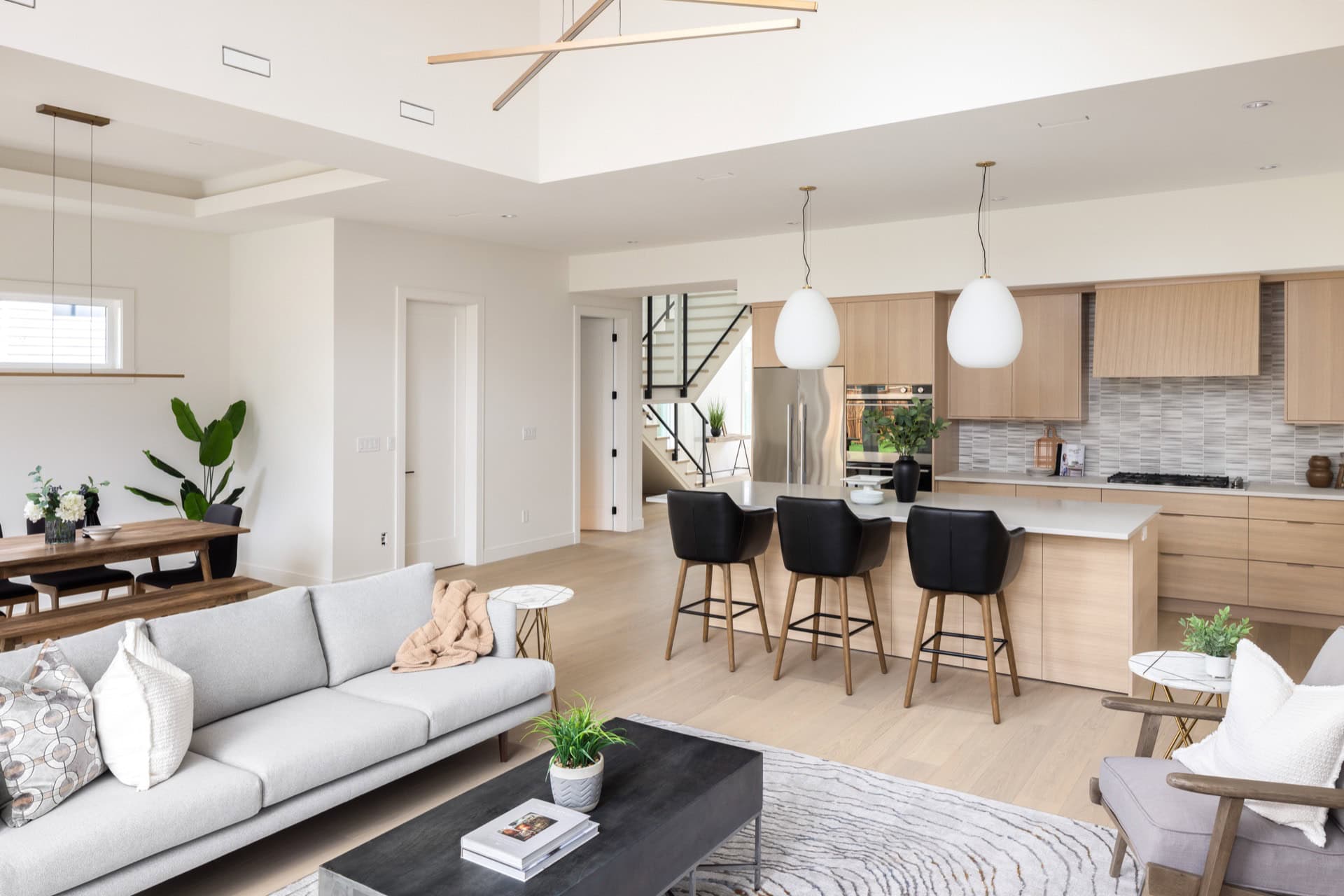 Bright open-concept living room and kitchen with modern white and wood finishes in a new Victoria BC home.