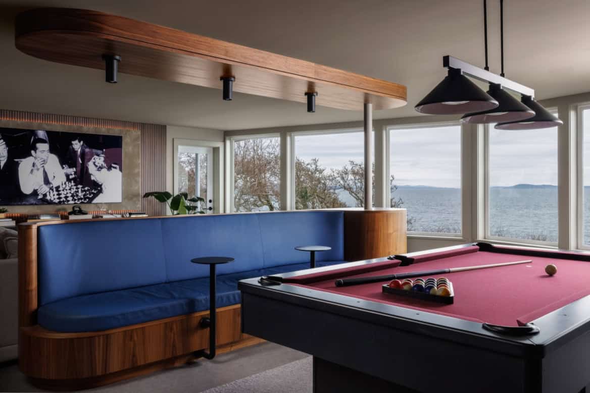 Modern home interior with pool table, blue curved seating, and waterfront view in Victoria BC.