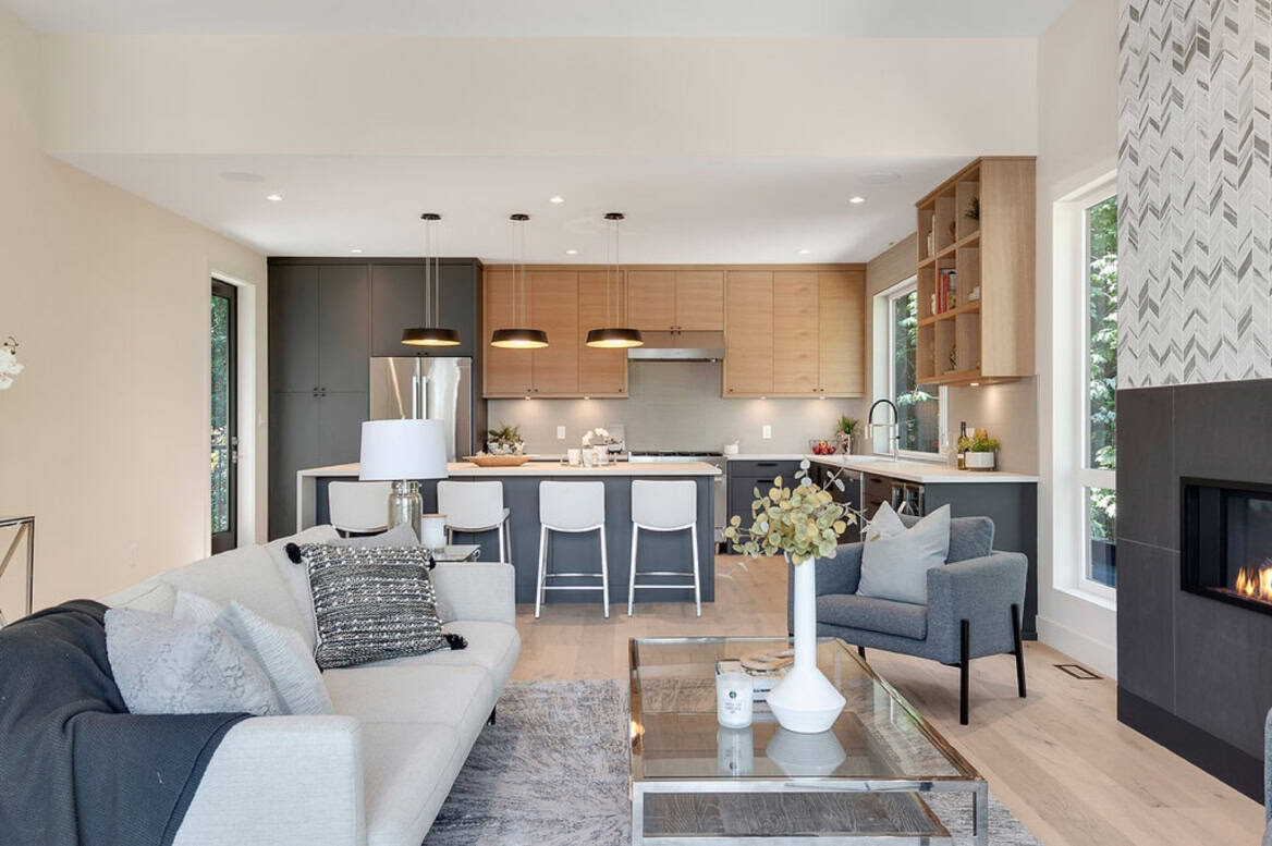 Open-concept living area with kitchen island, grey and wood tones, and fireplace in the Canopy project.