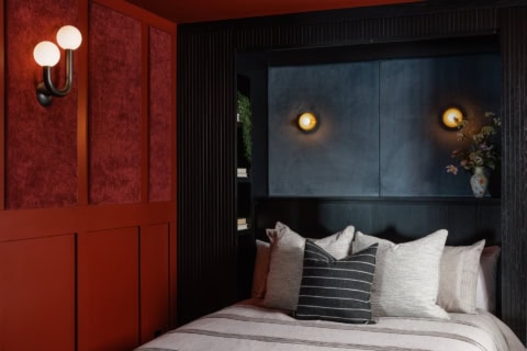 Luxurious bedroom with dark blue headboard, red wall panels, and soft cushions.