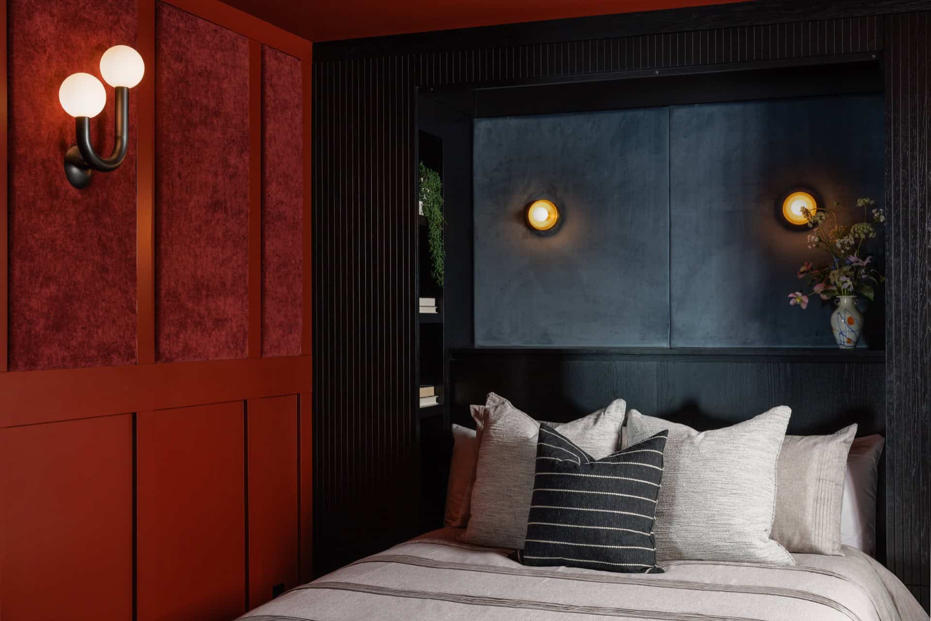 Luxurious bedroom with dark blue headboard, red wall panels, and soft cushions.