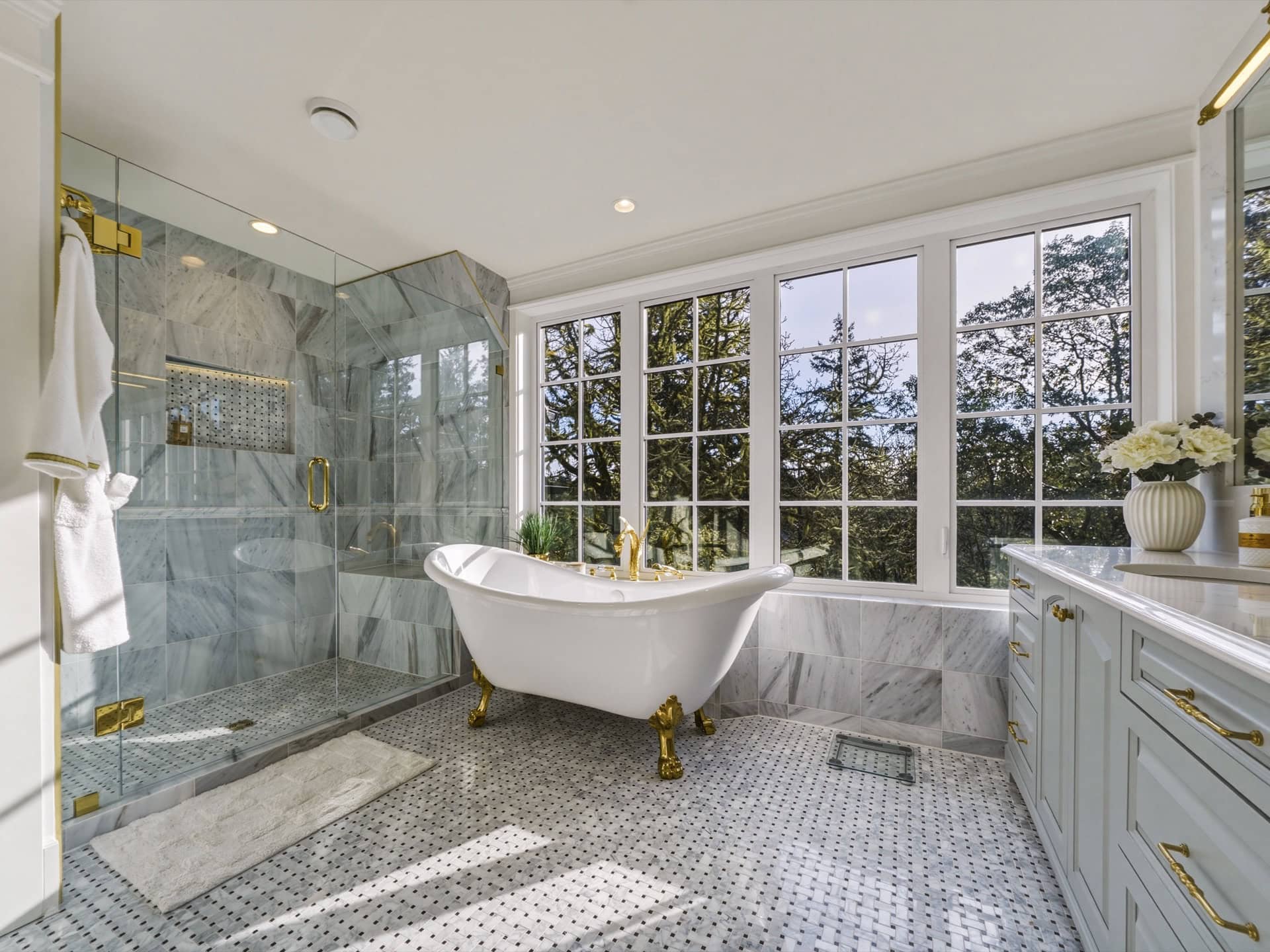 Elegant marble bathroom with freestanding clawfoot tub and large windows in Victoria BC home.