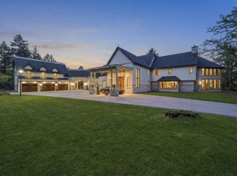Victoria BC custom home exterior at sunset with stone accents and illuminated entrance.