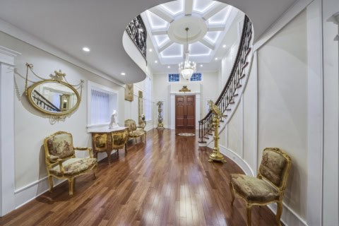 Elegant Victorian-inspired foyer with curved staircase, ornate chairs, and chandelier in The Parkwood Estate.