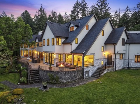 White Wolf Homes custom house in Victoria BC with lit windows and landscaped yard at dusk.