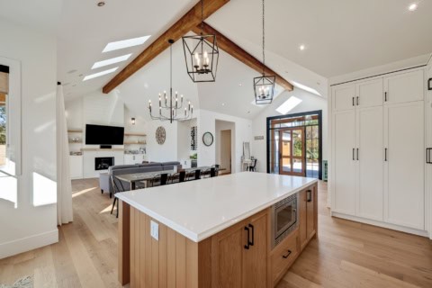 Open-concept kitchen with oversized island, vaulted ceiling, and modern lighting in a White Wolf Homes build.