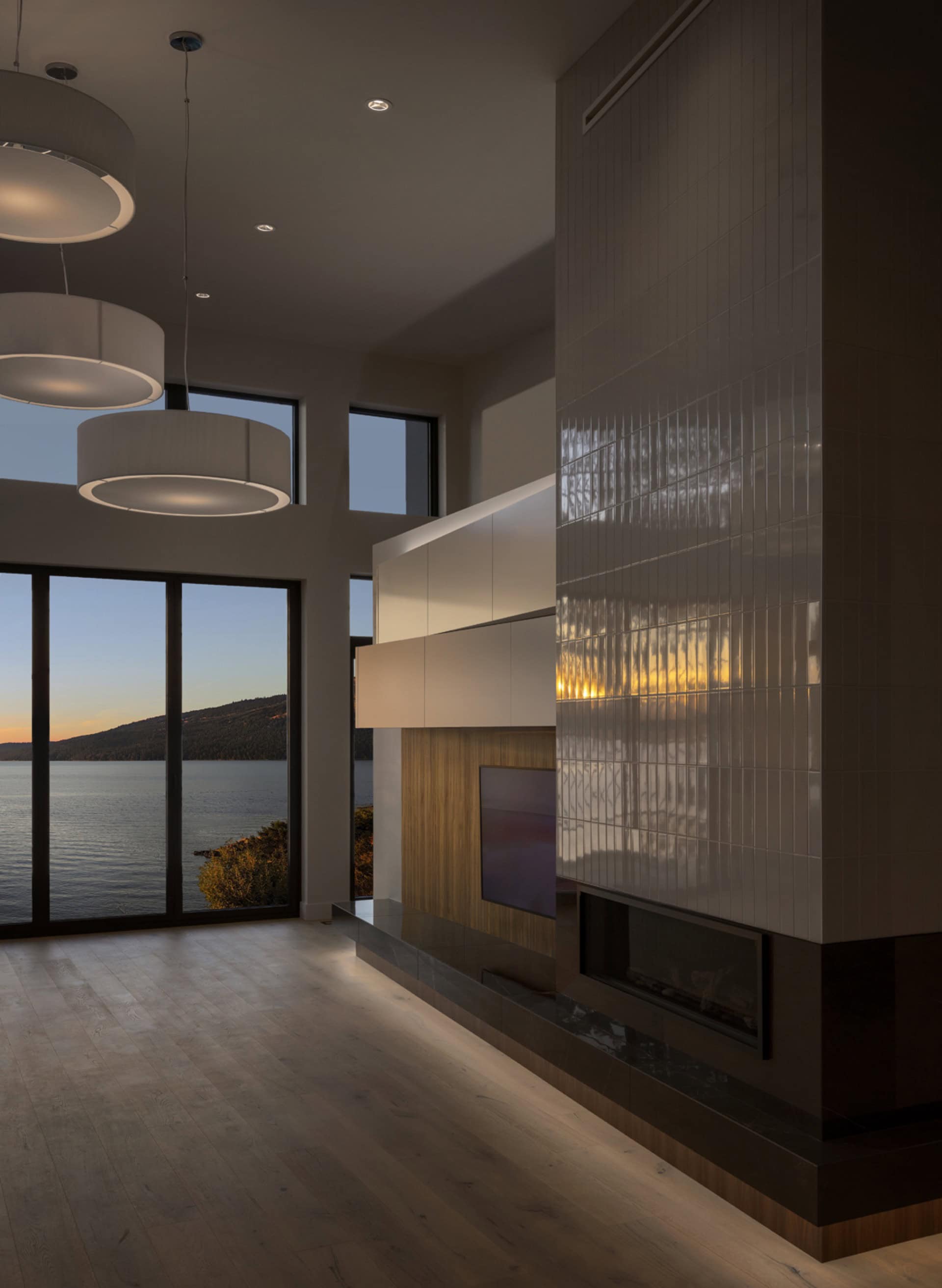 Modern living room with lake view and contemporary fireplace, Victoria BC home by White Wolf Homes.