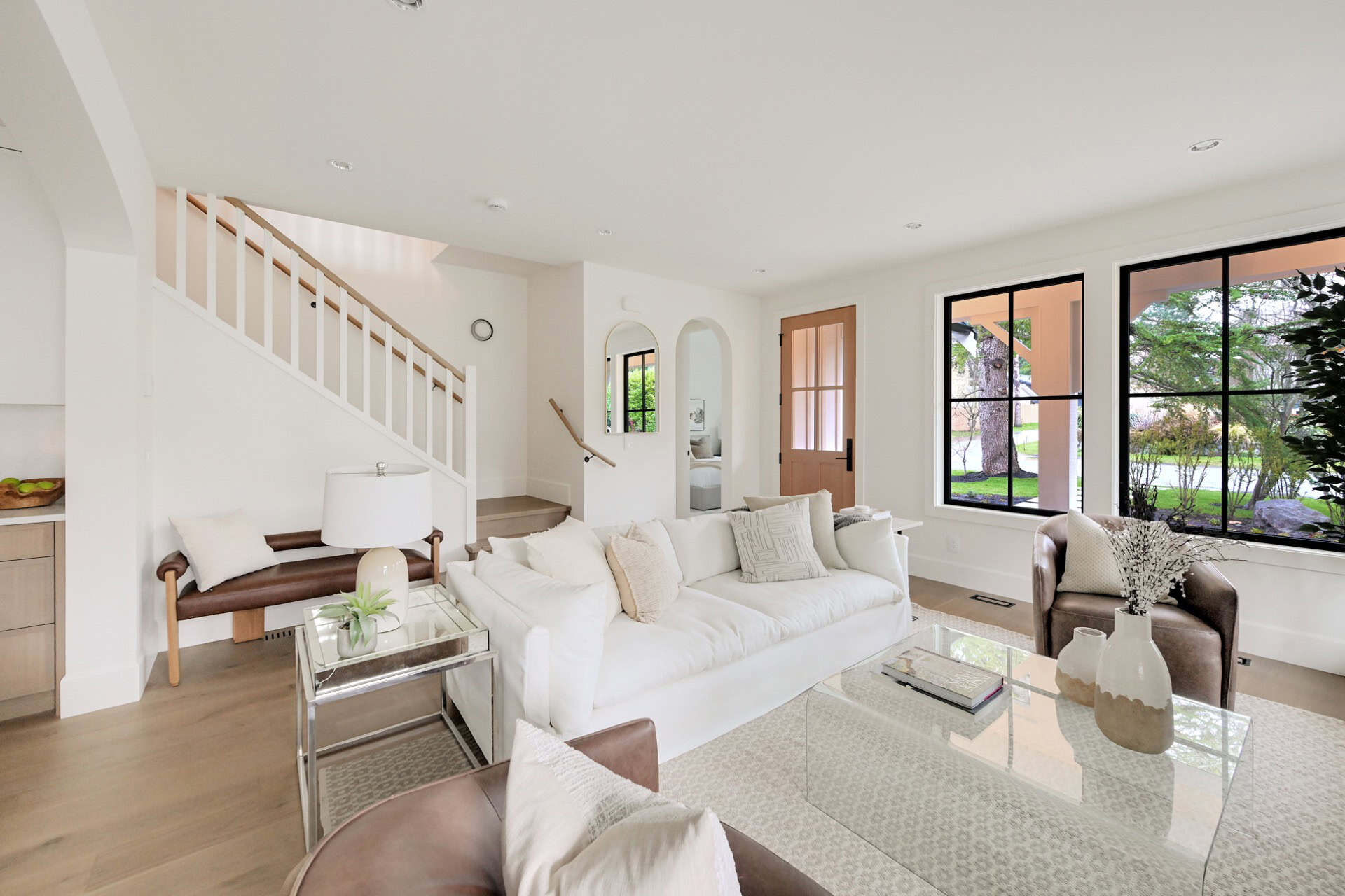 Bright interior with white sofa, glass coffee table and large windows in a modern Victoria BC home.