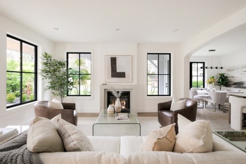 Spacious modern living room with white walls, black-framed windows, and a cozy fireplace.