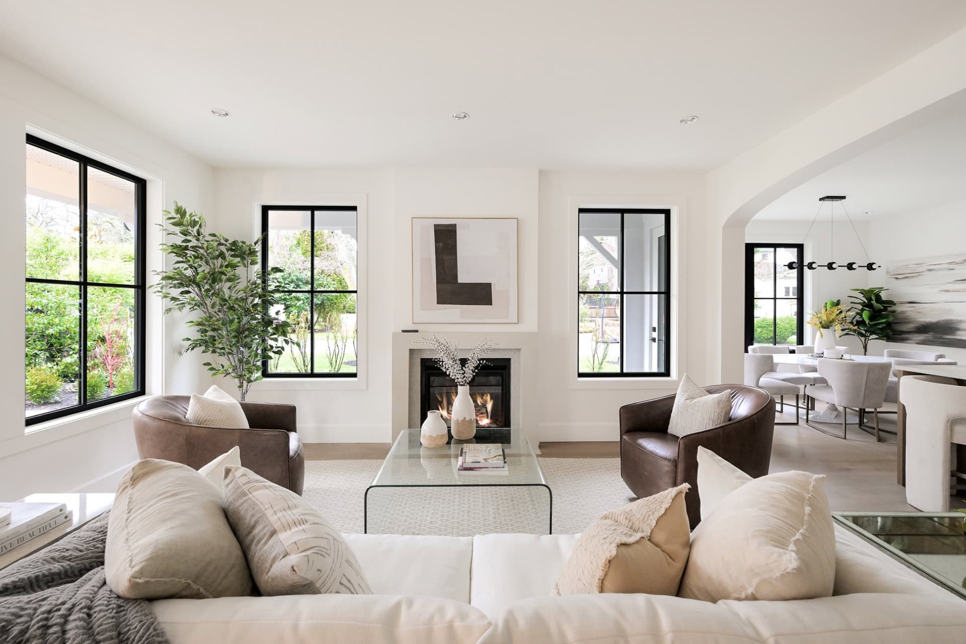 Spacious modern living room with white walls, black-framed windows, and a cozy fireplace.