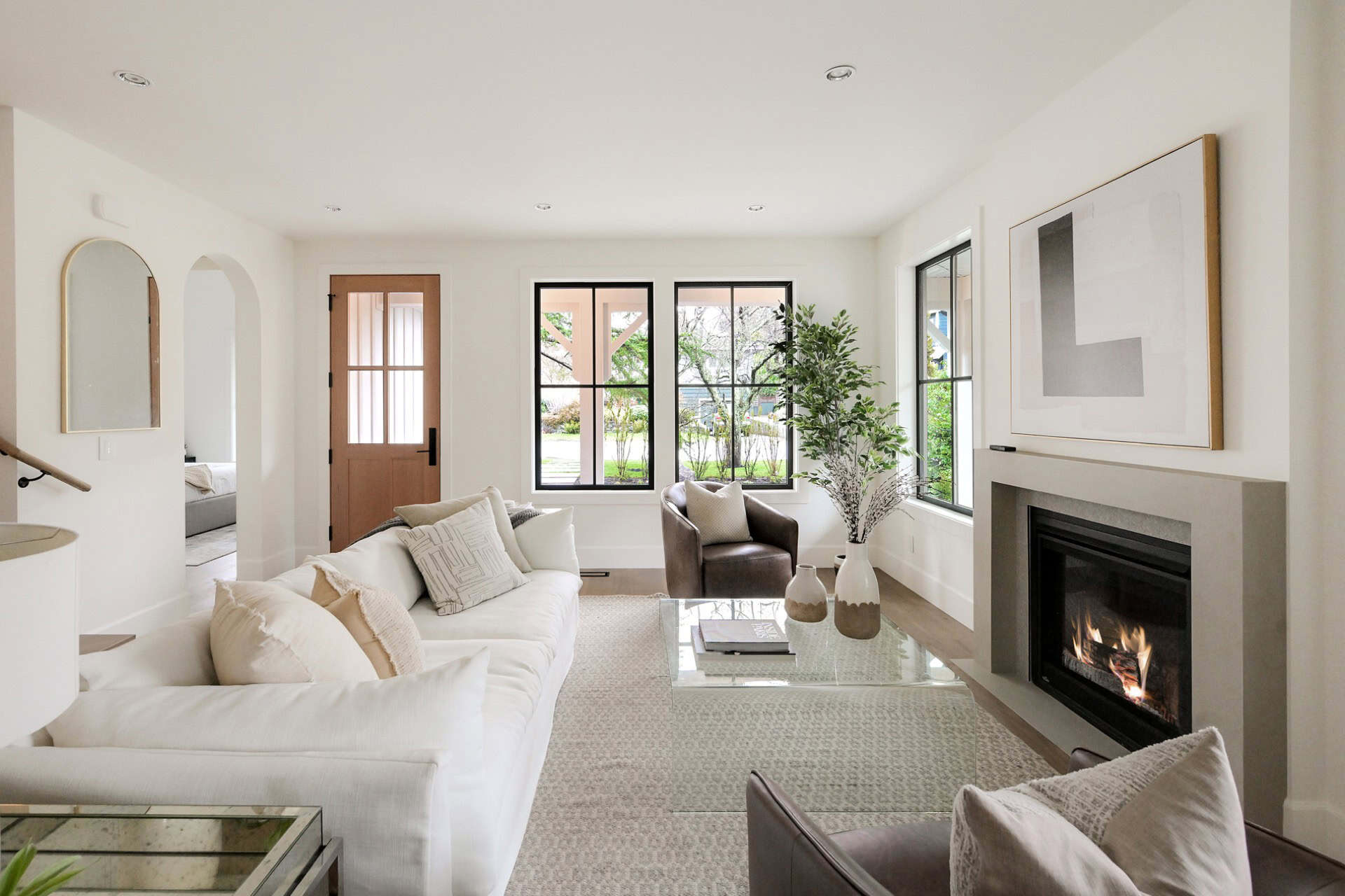Modern living room with white sofa, fireplace, and large windows in a Victoria BC home.