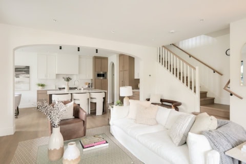 Living area of a modern home with white and neutral tones, open layout, and staircase in a Victoria BC home.
