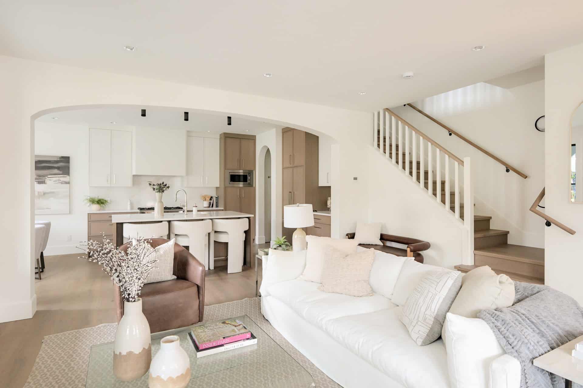 Living area of a modern home with white and neutral tones, open layout, and staircase in a Victoria BC home.