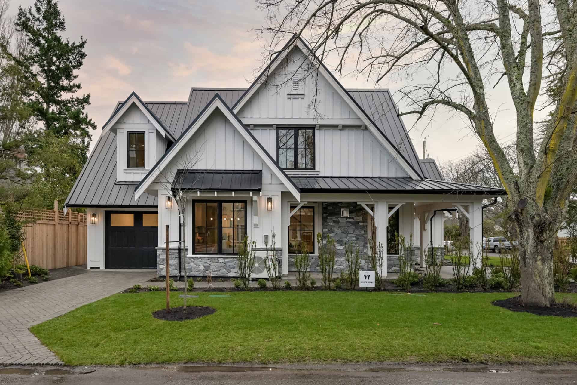 Custom Victoria BC home with white siding, gray roof, stone accents, front porch, and landscaped yard.