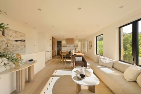 Bright open living room with large windows, neutral tones, and modern furniture by White Wolf Homes.