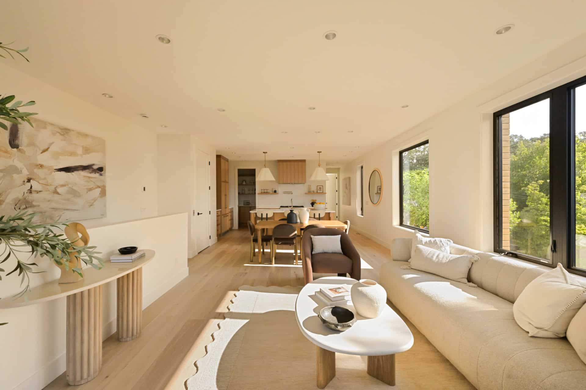 Bright open living room with large windows, neutral tones, and modern furniture by White Wolf Homes.