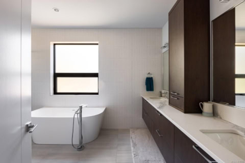 Modern bathroom with freestanding tub, double vanity and dark wood cabinets.