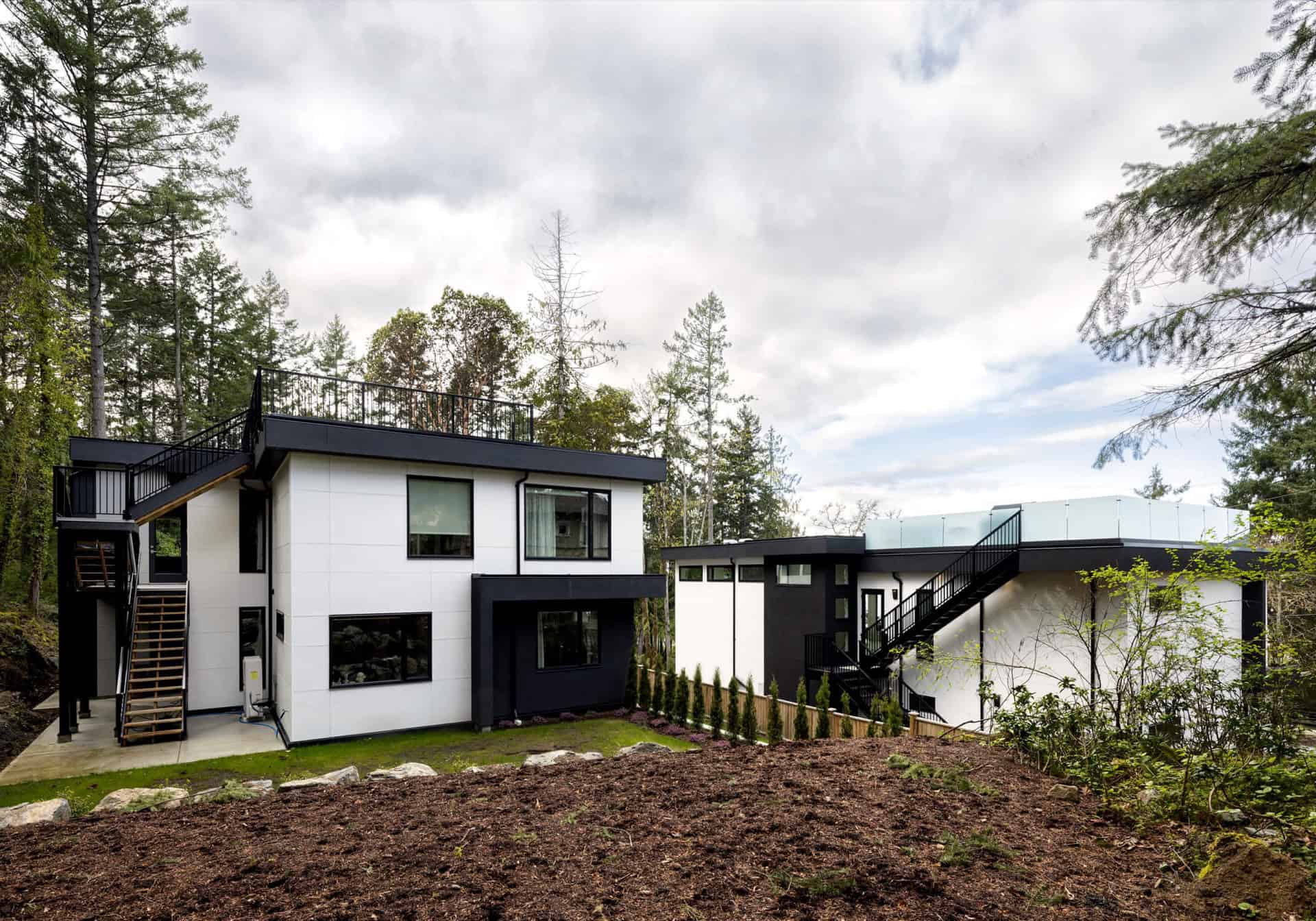 Modern two-story custom home exterior by White Wolf Homes in Victoria BC with white and black siding.