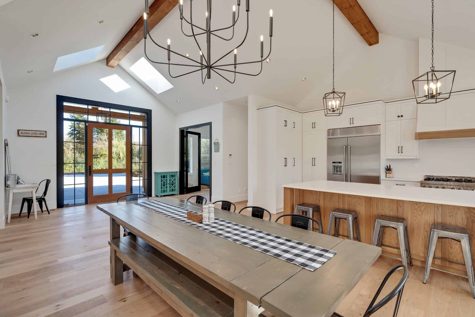 Bright modern kitchen and dining area with timber beams and a long rustic table.