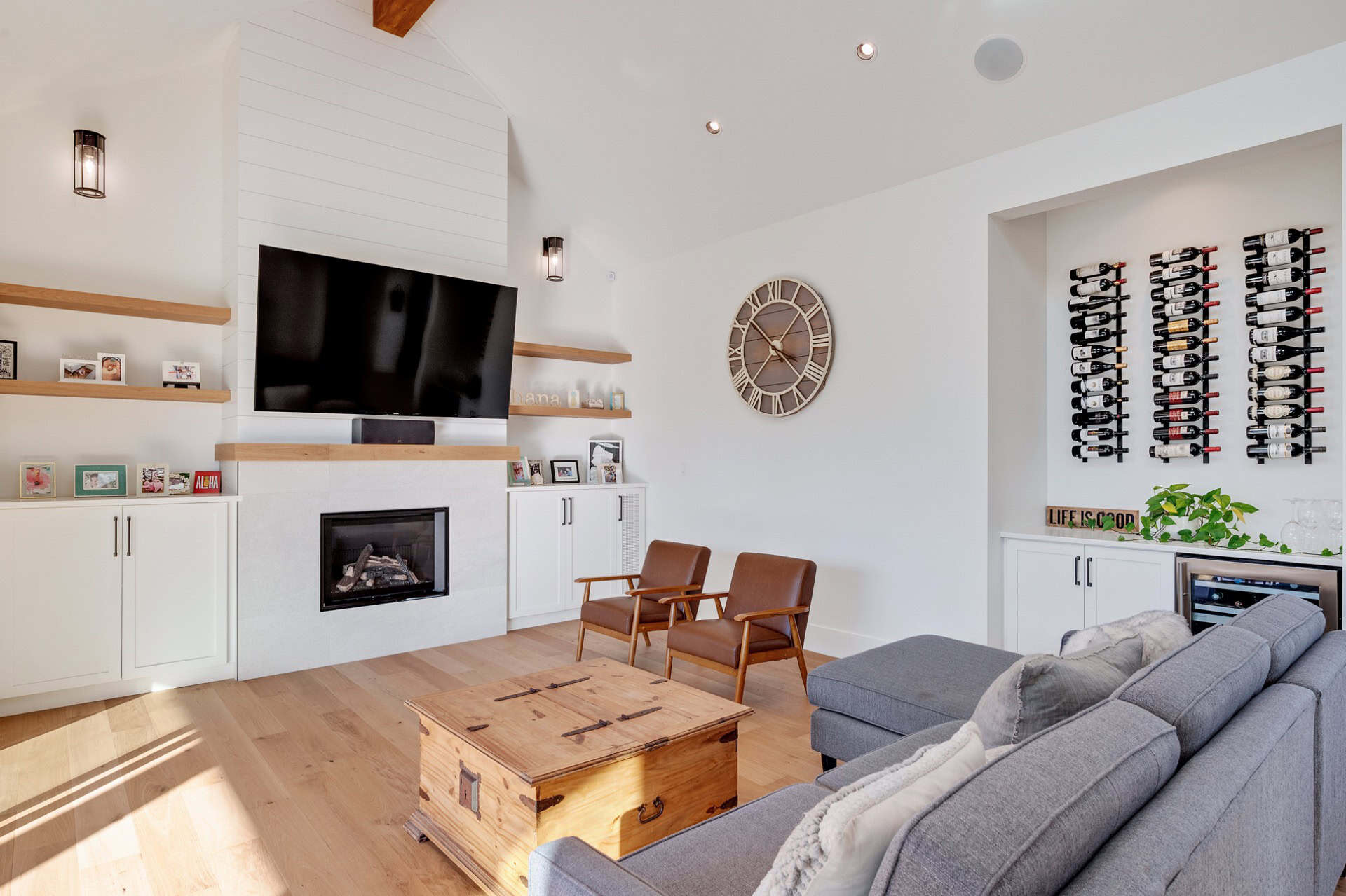 Bright modern living room with fireplace, mounted TV, and wine wall in a White Wolf Homes home.